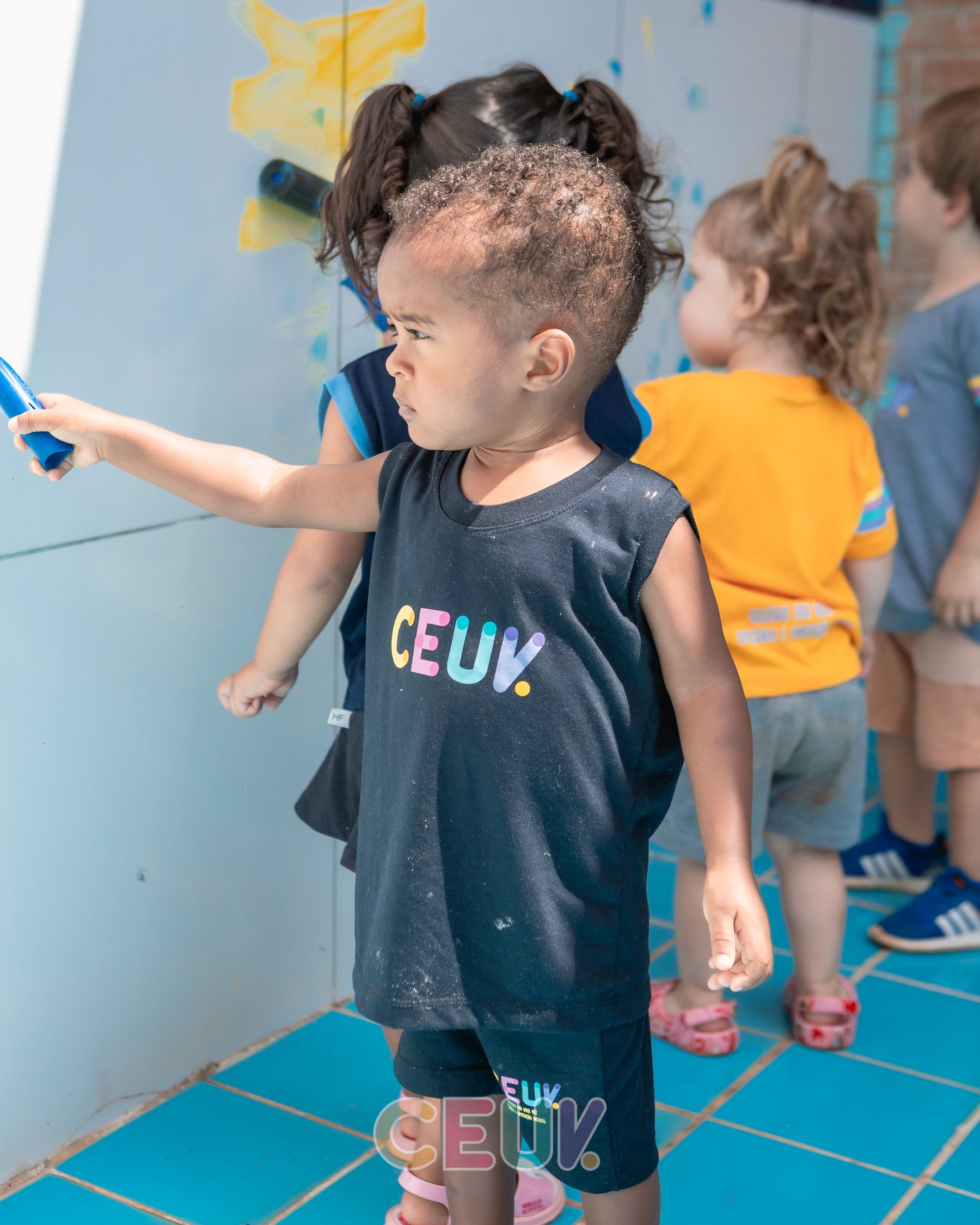 Criança do CEUV pintando parede colorida durante atividade sensorial